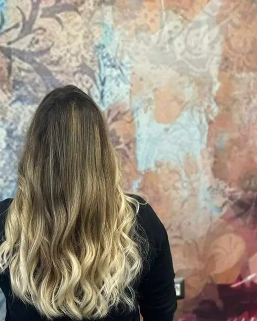 Balayage biondo su capelli lunghi mossi, vista da dietro